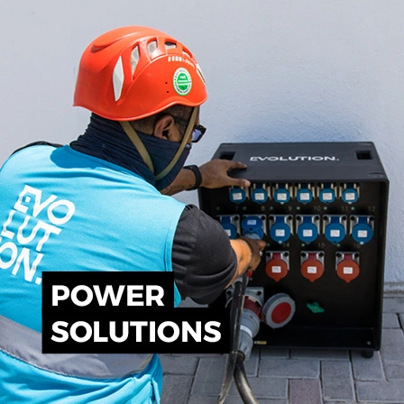 Electrical technician wearing protective equipment while working on a temporary event power distribution board.